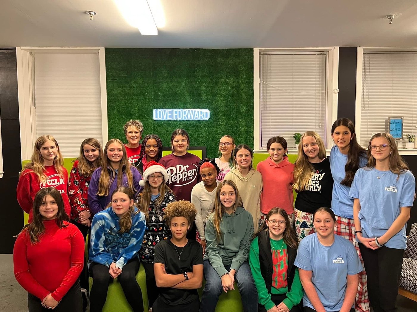 Community group under LOVE FORWARD neon sign